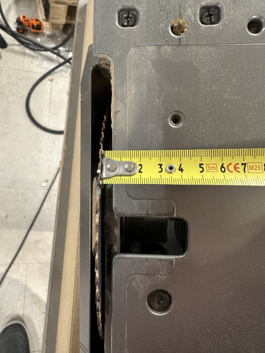 Måttband visar avstånd vid klingans kant på en kap- eller bordssåg, med mätning upp till cirka 7 cm på en arbetsbänk i bakgrunden.
