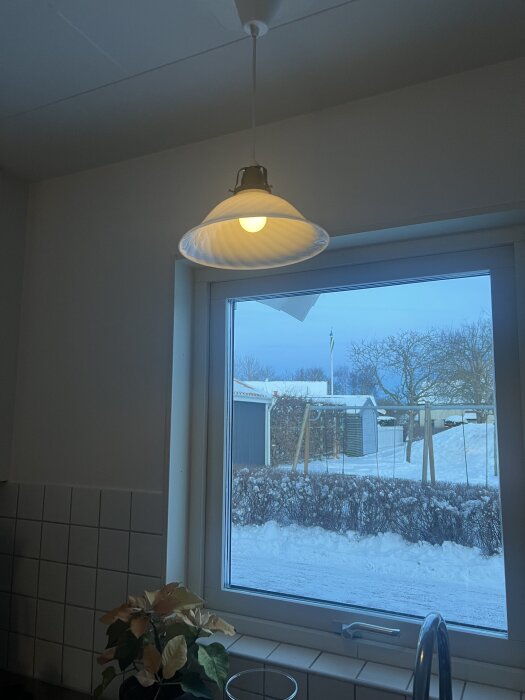 Taklampa och fönster med vinterutsikt utanför köket.