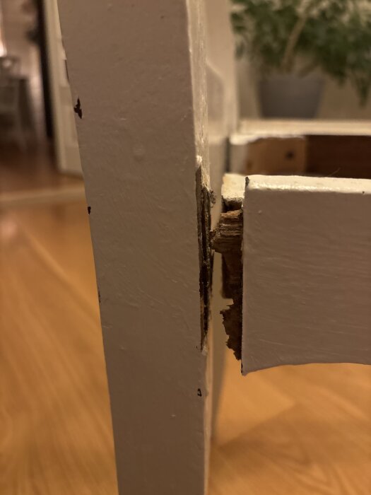 Närbild på en skadad köksstol med flisigt material vid en av delarna som går in i stolens baksida.
