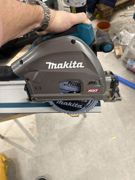Bild på en Makita cirkelsåg med sågklingan synlig. Personen håller i sågen i en verkstadsmiljö.