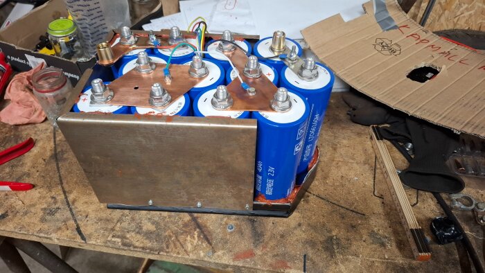 Hemmagjort lithiumtitan-batteri under konstruktion på en arbetsbänk, med flera celler kopplade med kopparkablar.