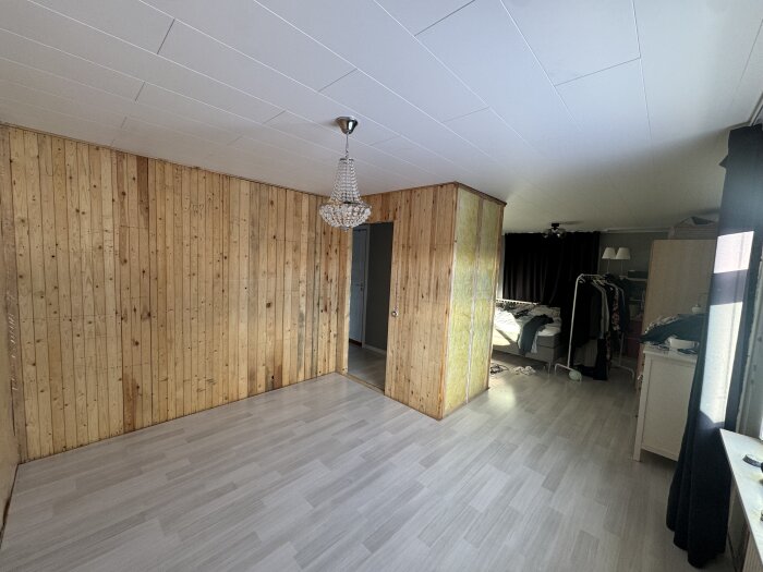 Rum under renovering med träväggar och dörröppning, tänkt som blivande pojkrum, med plats för garderob till höger.