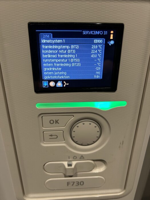 Nibe F730 värmepumps display visar servicemeny och temperaturer, inklusive framledningstemp och rumstemperatur, med en lysande grön indikator.