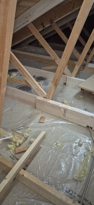 Byggråstruktur av träbalkar i ett loft, visar förstärkta över- och underramar under pågående renoveringsprojekt.