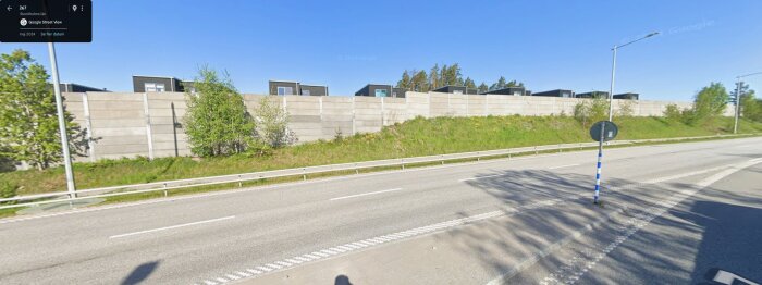Betongbullermurar längs en väg i Stäkethöjden, omgivna av grönska, med bostäder synliga ovanför murarna.