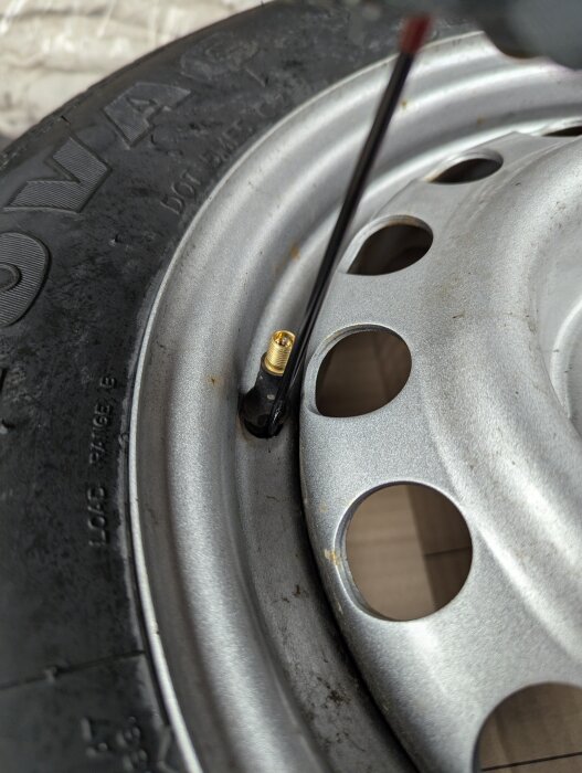 Närbild på ett däck och en fälg med en nyinstallerad ventil. Verktyg används för att sätta fast ventilen korrekt.