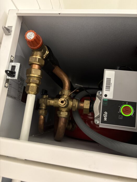 VVS-komponenter och en Wilo-pump i ett skåp, fokus på rör och ventiler.