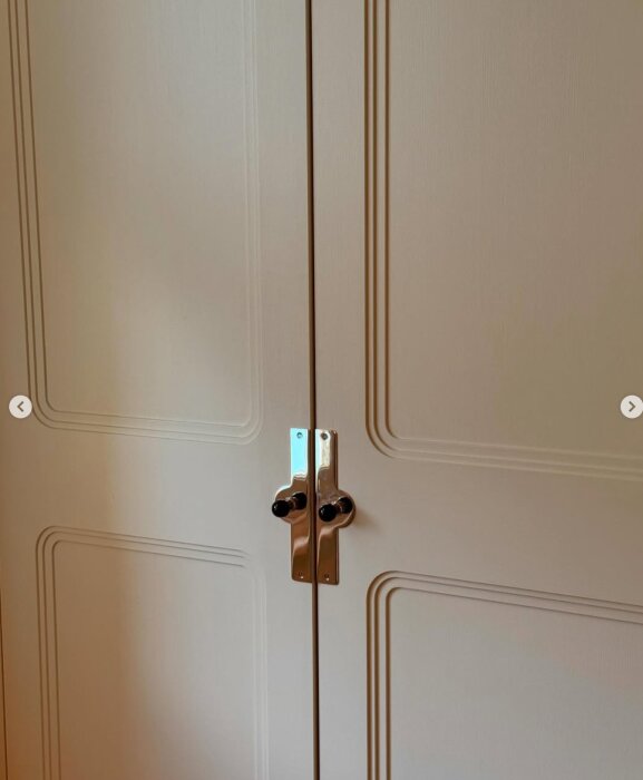 Närbild av två garderobsdörrar med spegeldesign och enkla handtag i metall.