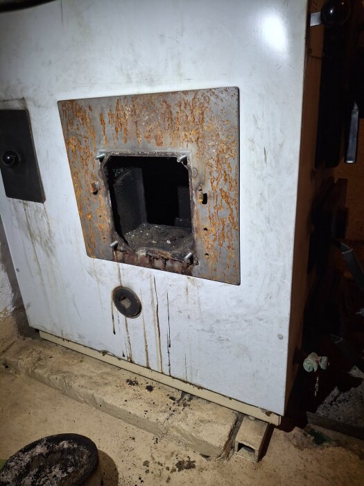 Rostig Albin villacombi panna utan lucka, sedd från sidan, där en pelletsmodul tidigare installerats..matcher konstruerat för vedeldning.