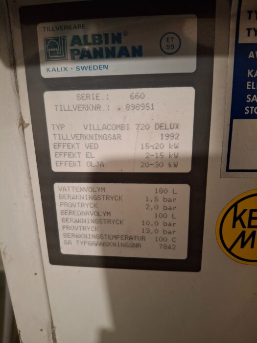 Etikett på Albin Villacombi 720 Delux panna, visar specifikationer som tillverkningsår 1992, effekt för ved, el, olja, och vattenvolym.