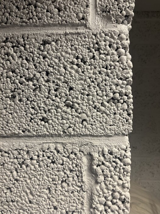 Närbild av en vägg byggd av lättklinkerblock med en grov, ojämn yta och tydliga fogar.