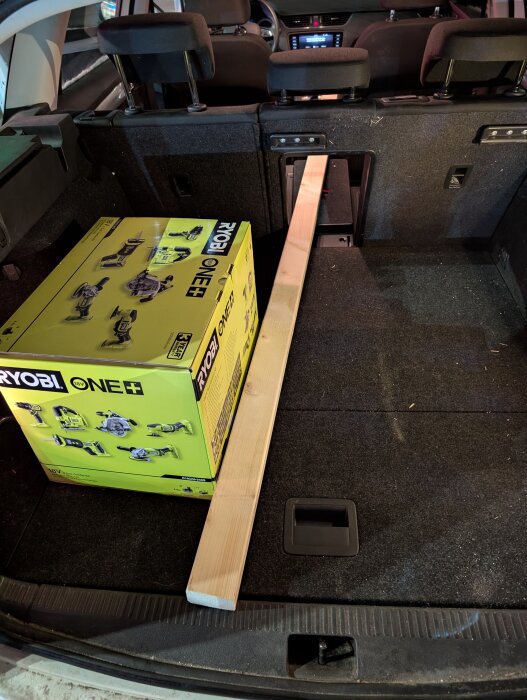 Kartong med Ryobi One+ verktyg och en regel i bakluckan på en bil.