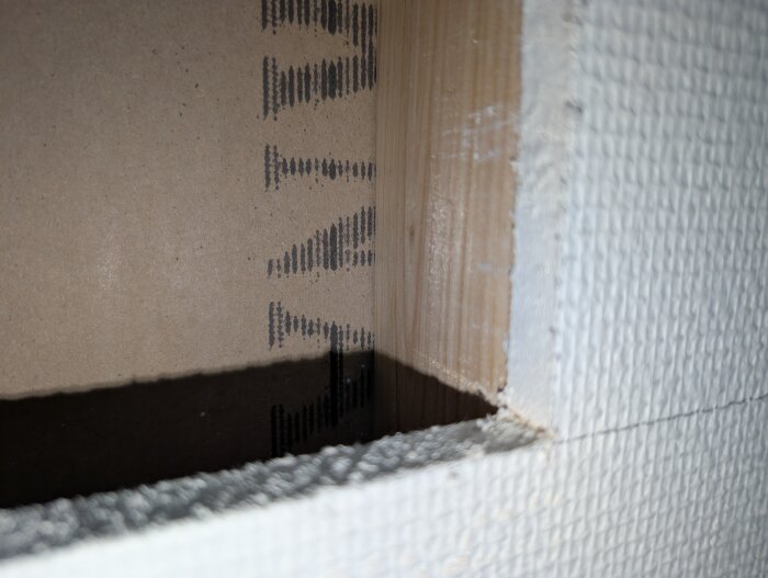 Utsågat hörn i vägg med uppmärkta linjer, visar mätt 20 cm avstånd i byggprojekt.