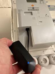 En hand kopplar in en nätverkskabel i en elmätare för att aktivera HAN-porten, vilket liknar att ansluta en kabel till en dator.