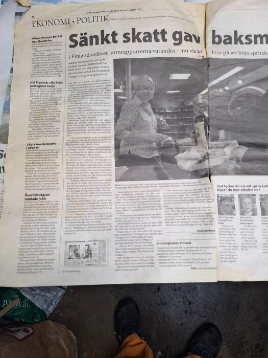 Tidningsartikel om Finlands sänkta alkoholskatt från 2004, med rubrik och foto av person i butik.