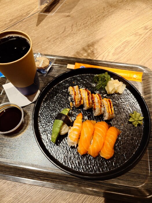 Sushitallrik med nigiri och maki samt soja och dryck på bord, middag vald av yngsta sonen.