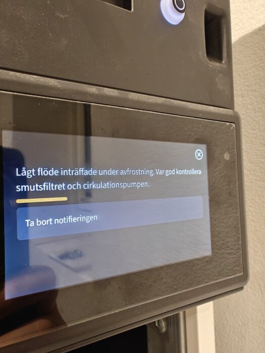 Digital display på värmepump visar felmeddelande om lågt flöde under avfrostning; instruktion att kontrollera smutsfilter och cirkulationspump.
