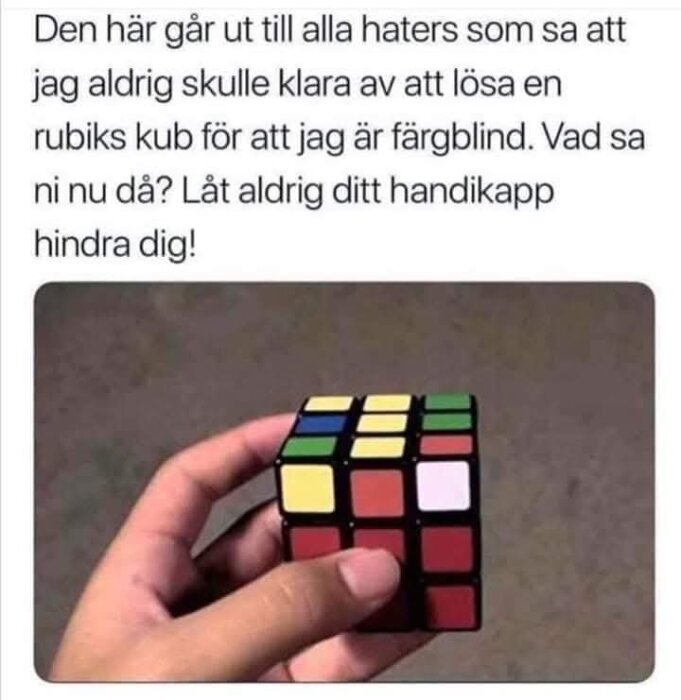 En hand håller en Rubiks kub med flera färgade rutor, över en text om att övervinna hinder trots färgblindhet.