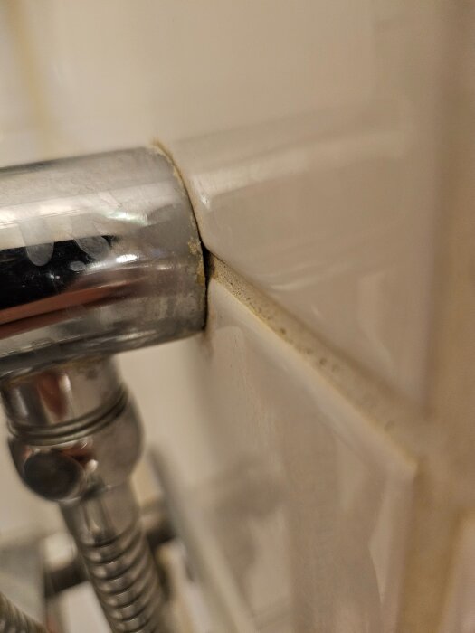 Lös duschstång monterad i väggen med synlig springa, visar nära bild av badrumsmonteringens stabilitetsproblem.
