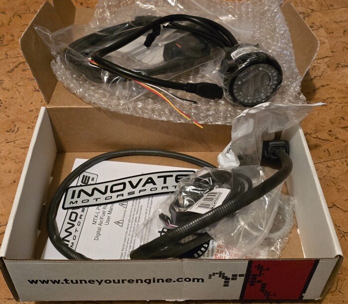 Innovate Motorsports bredbandlambda MTX-L kit med kablar och manual, i en öppen kartong på golv.