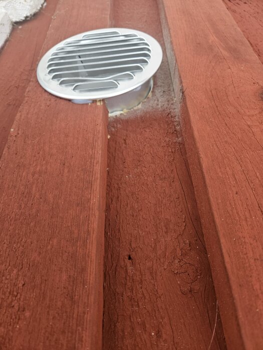 Ventilgaller monterat på röd träfasad, synligt ovanför bottenbrädan.