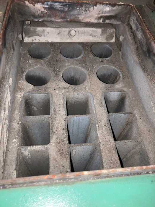 Pellet burner interior showing multiple round and square outlet tubes with soot deposits.