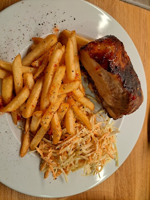 Tallrik med grillat kött, krispiga pommes frites och krämig coleslaw, kryddad med svartpeppar och chiliflakes.