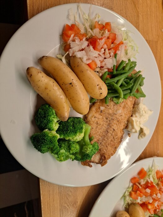 Tallrik med stekt fisk, tre potatisar, broccoli, gröna bönor, sallad med paprika och lök, samt majonnäs.