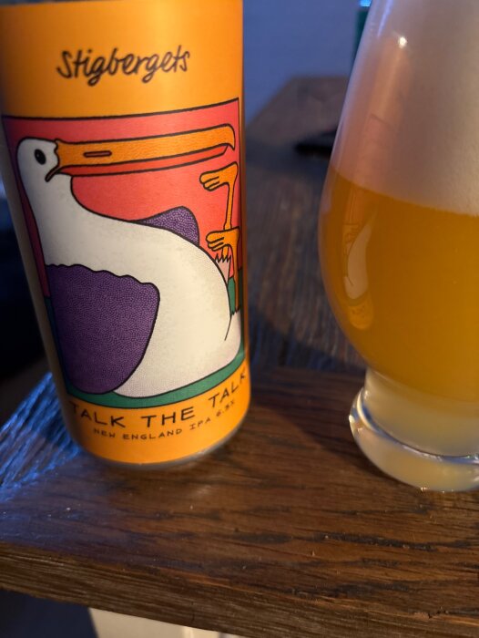 Burk med Stigbergets Talk the Talk New England IPA och ett glas med öl på ett bord.