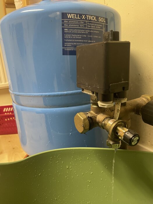 Blå hydropress med märketikett, kopplingar och säkerhetsventil som läcker vatten.