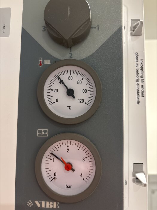 Nibe EVC 13 panel med två mätare, en för temperatur i grader Celsius och en för tryck i bar, samt en justeringsknapp överst.