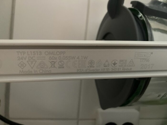 Närbild av IKEA Omlopp köksbelysningstyp L1513, med produktinformation och symboler synliga på armaturen.