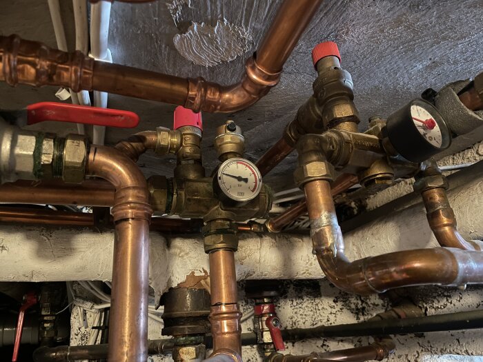 Rörinstallation med kopparrör, en tryckmätare och ventiler. Eventuellt läckande övertrycksventil på grund av droppande vatten.