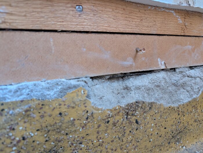 Spricka mellan träpanel och betongvägg i ett garage, där fuktskador undersöks efter installation av en luft-luft värmepump.