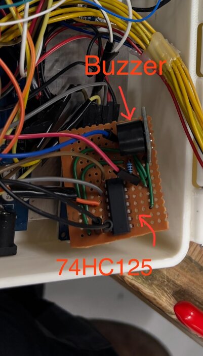 Kretskort med anslutna kablar visar en buzzer och en 74HC125-chip monterad på prototypkort inuti styrbox.