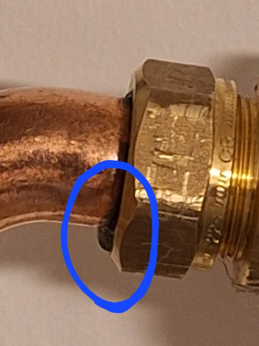 Kopparrör med blå cirkelmarkerad droppande läcka vid anslutning.