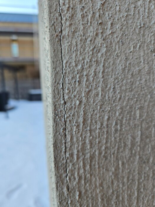 Sprickor i putsvägg där två kortsidor möts, troligen orsakade av rörelse vid putsarbetet, med synligt mönster från tidigare arbetsmoment.