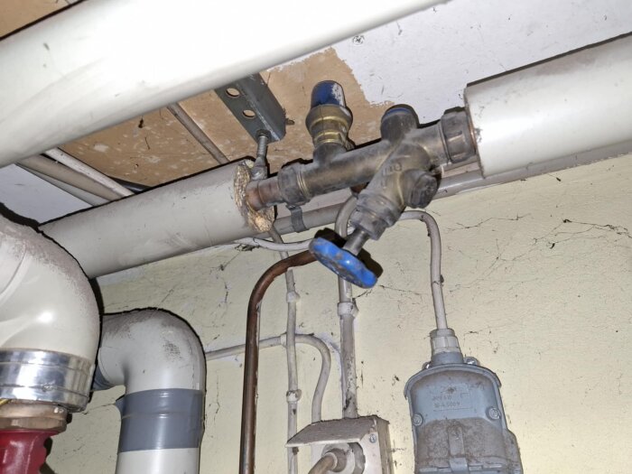 Blå ventil på kopparrör i system för uppvärmning av vatten; kopplad till isolerat rör och grå plaströr. Ventilens funktion diskuteras i byggforum.
