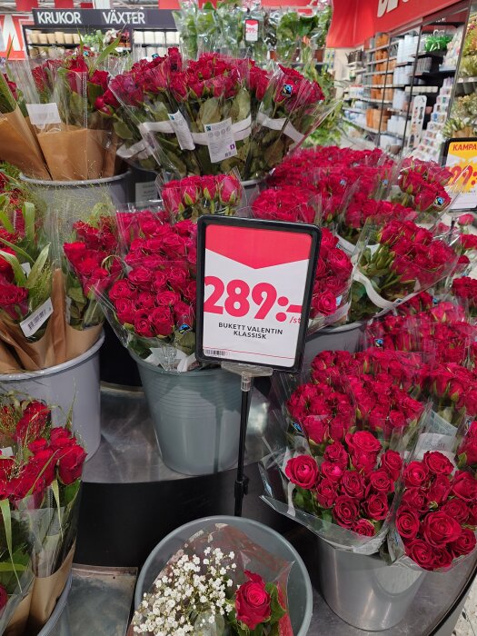 Bukett med röda rosor i butik med prisskylt för 289 kr, omgivet av flera liknande buketter.