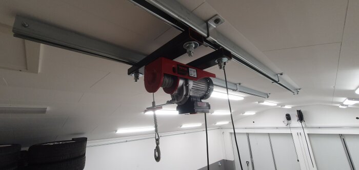 Trådlös vinsch installerad i ett garage tak med skjutportskenor för att flytta och lyfta tunga föremål enkelt.