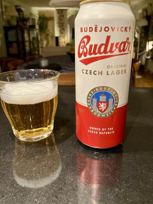 En ölburk med Budějovický Budvar Original Czech Lager och ett glas öl på ett bord i ett rum.