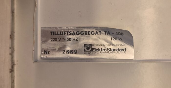 Etikett på tilluftsaggregat Elektrostandard TA-400, 220V, 50Hz, 120W, med modellnummer 2669, visar produktinformation och logotyp.
