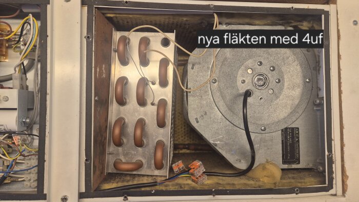 Tilluftsaggregat från 1985 med ny fläkt installerad, märkt "nya fläkten med 4uf", omgivet av kopplingssladdar och elsystem.