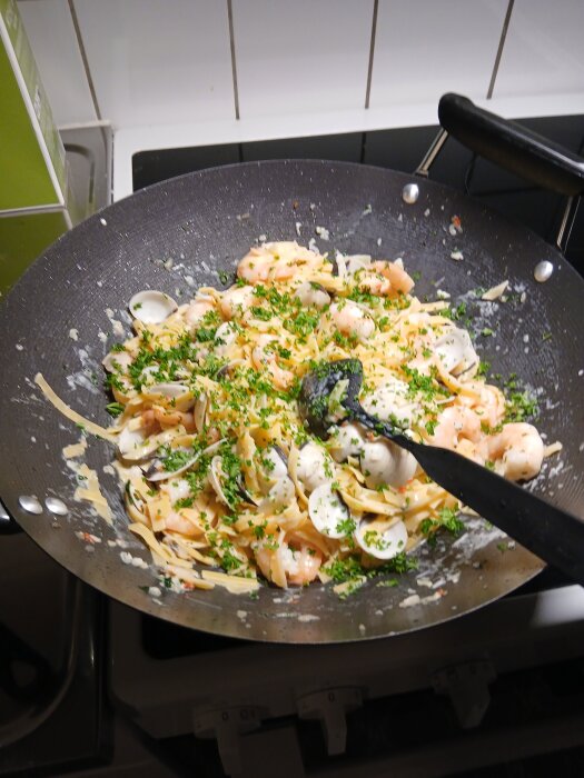 Pasta med räkor, svamp och grönsaker i en stekpanna, toppad med hackad persilja.