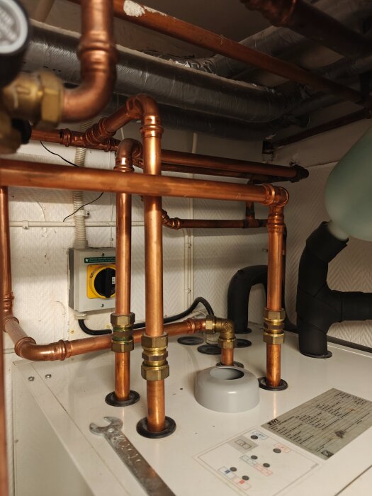 Kopparrör och ventiler i ett tekniskt rum, del av uppvärmningssystem; inga tecken på bränt eller trasigt elektronik.