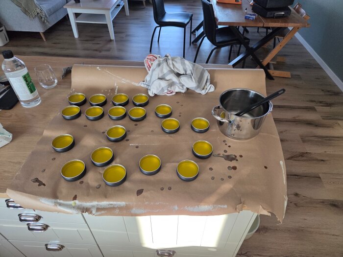 Köksbord med flera burkar innehållande åländskt bivax board butter, en kastrull med slev och en flaska.