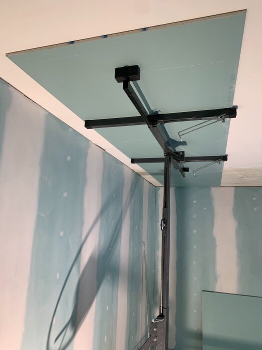 Gipsskiva monterad i tak med gipshiss i ett rum under renovering, med redan uppsatta gipsväggar.