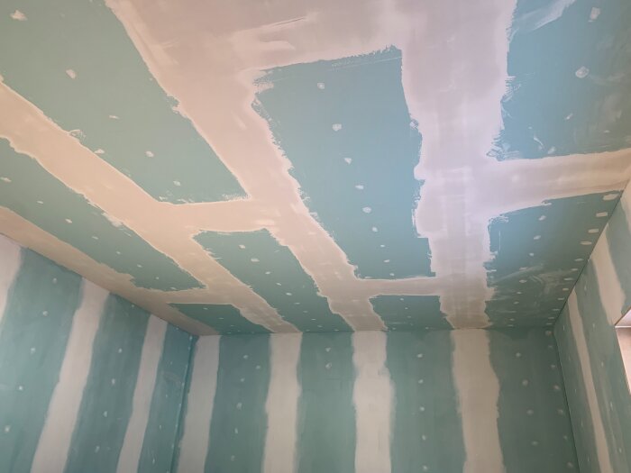 Tak och väggar med gips och nyligen spacklade fogar i ett rum under renovering.