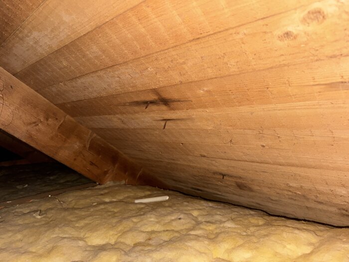 Träreglar med masonitskiva i snettak på vind, sett ovanifrån med isolering under.