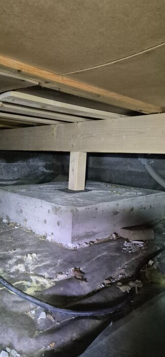 Förstärkning i krypgrund med träpelarfundament på betongblock.